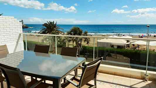 En møbelgruppe på en altan med udsigt til stranden og havet. (AI-genereret tekst)