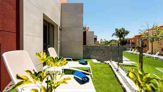 Liggestole med blå håndklæder på en græsplæne nær et hus. (AI-genereret tekst)