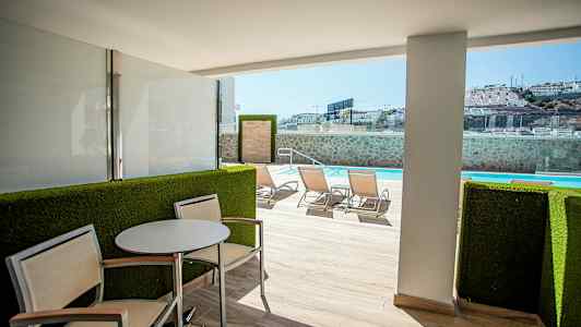 Udendørsterrasse med siddeområde og udsigt til swimmingpool. (AI-genereret tekst)