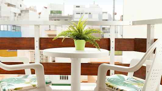 En altan med et bord og to stole, en grøn potteplante på bordet. (AI-genereret tekst)