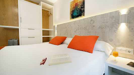 Soveværelse med hvid dobbeltseng, orange puder og åben garderobe. (AI-genereret tekst)