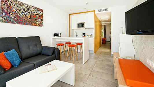 Et moderne hotelværelse med en siddegruppe, køkken og fjernsyn. (AI-genereret tekst)