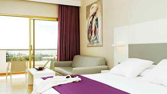 Hotelværelse med en seng, en sofa og en balkon med udsigt. (AI-genereret tekst)