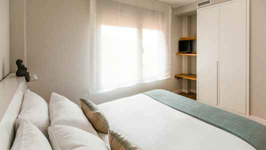 Moderne soveværelse med et stort vindue, et skab og hylder med et lille fjernsyn. (AI-genereret tekst)