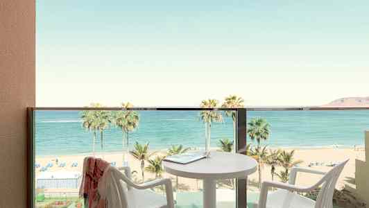 Altan med udsigt over strand og hav, bord og stole er synlige. (AI-genereret tekst)