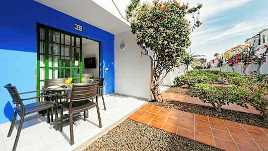 Terrasse med bord og stole, omgivet af planter og blomster. (AI-genereret tekst)