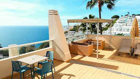 Terrasse med havudsigt, siddepladser og liggestole. (AI-genereret tekst)