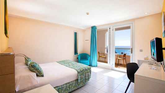 Et hotelværelse med en seng, et skrivebord og en stol. Vindue med havudsigt. (AI-genereret tekst)