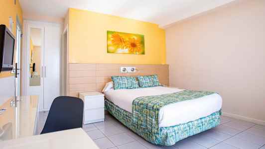 Et hotelværelse med en dobbeltseng, vægmaleri af blomster over sengen og lyse vægge. (AI-genereret tekst)