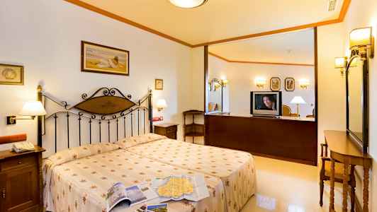 Et hotelværelse med en dobbeltseng, natbord og et fjernsyn på en møbel. (AI-genereret tekst)