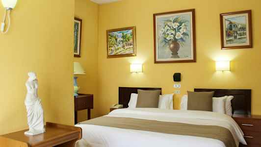 Et hotelværelse med en dobbeltseng, dekorerede vægge med malerier og en lille statue på et møbel. (AI-genereret tekst)