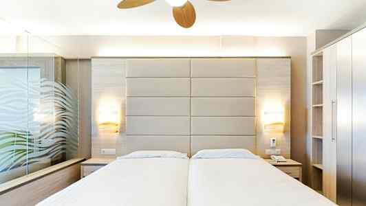 Hotelværelse med to enkeltsenge, moderne indretning og loftsventilator. (AI-genereret tekst)