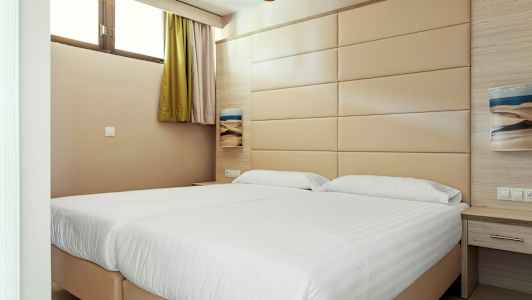 Et hotelværelse med to senge og en beige vægpanel. (AI-genereret tekst)