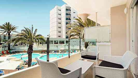 Udsigt fra en terrasse med siddeområde, swimmingpool og omkringliggende bygninger. (AI-genereret tekst)