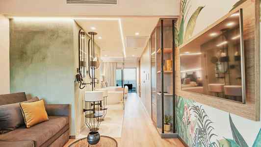 Interiøret i et stilfuldt hotelværelse med sofa, spejle og et TV på væggen. (AI-genereret tekst)