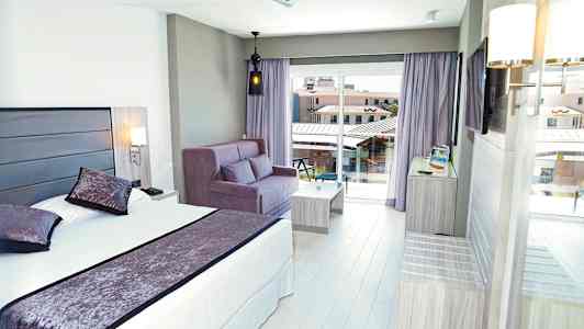 Hotelværelse med seng, sofa og altanudsigter. (AI-genereret tekst)