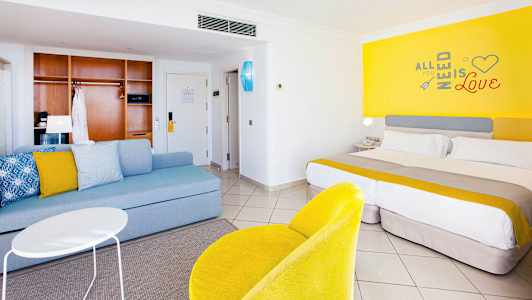 Hotelværelse med moderne indretning, herunder en seng, siddeområde og farverige detaljer. (AI-genereret tekst)