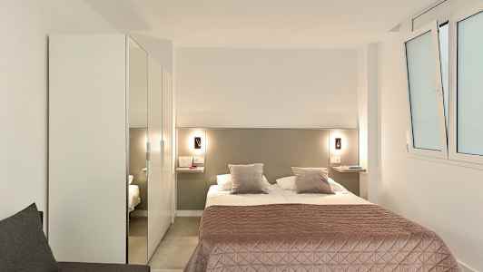 Et hotelværelse med en dobbeltseng, et rosa sengetæppe og et skab. (AI-genereret tekst)