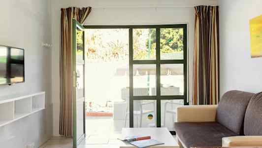 Billedet viser en stue med åbne døre ud til en terrasse. (AI-genereret tekst)