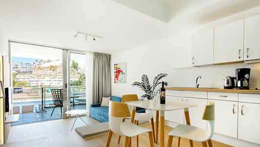 Lyst indrettet hotelværelse med køkkenområde og altan med udsigt. (AI-genereret tekst)