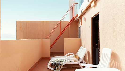 Privat terrasse med solsenge, tæppe og taske. (AI-genereret tekst)