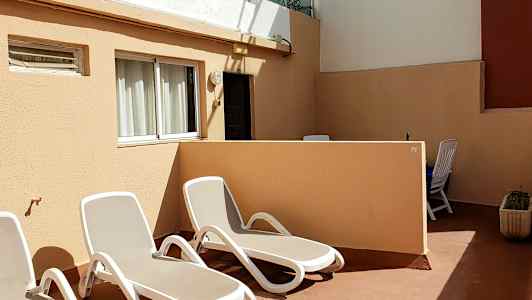 En terrasse med liggestole og bord med stole. (AI-genereret tekst)