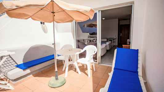 Terrasse med bord, stole og solseng. (AI-genereret tekst)