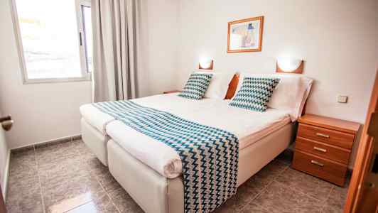 Dobbeltværelse med to enkeltsenge, natbord og vindue. (AI-genereret tekst)