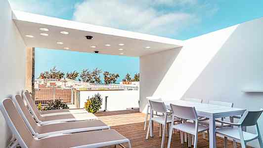 Terrasse med liggestole og et spisebord med stole under en hvid tagoverdækning. (AI-genereret tekst)