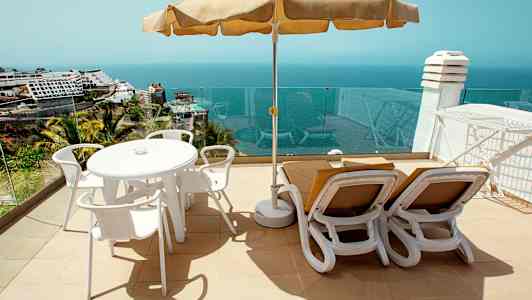 Solterrasse med bord, stole og liggestole samt havudsigt. (AI-genereret tekst)