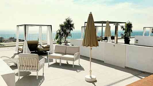 En terrasse med liggestole, parasol og udsigt over havet. (AI-genereret tekst)