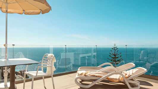 Terrasse med liggestole, parasol og havudsigt. (AI-genereret tekst)