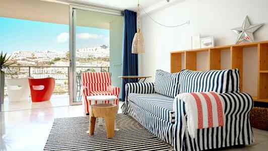 En stue med en sofagruppe foran en glasdør, der fører ud til en altan. (AI-genereret tekst)