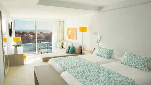 Lyst hotelværelse med dobbeltseng, siddeområde og balkon med havudsigt. (AI-genereret tekst)