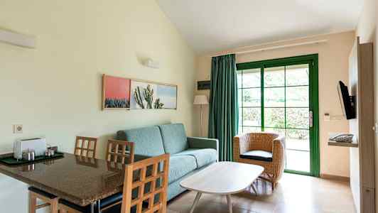 Værelse med siddepladser og spisebord, afbilledet med grøn dør og interiør. (AI-genereret tekst)