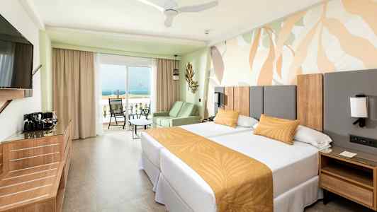 Hotelværelse med to enkeltsenge og en balkon med udsigt til havet. (AI-genereret tekst)