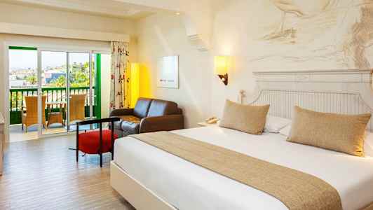 Et hotelværelse med en dobbeltseng, en siddegruppe og en balkon. (AI-genereret tekst)