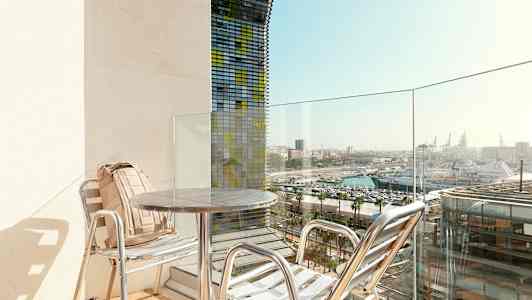 En altan med to stole og bord, med udsigt over havnen. (AI-genereret tekst)