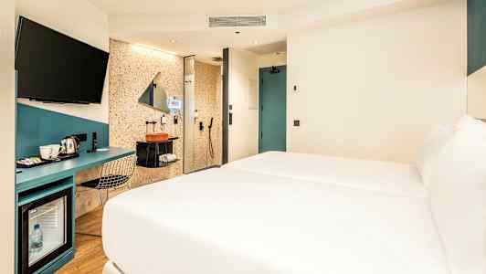 Hotelværelse med seng, skrivebord og badeområde. (AI-genereret tekst)