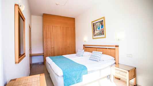 Hotelværelse med en dobbeltseng, trædetaljer og et skab. (AI-genereret tekst)