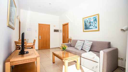 Et hotelværelse med en sofa, et spisebord og et tv. (AI-genereret tekst)