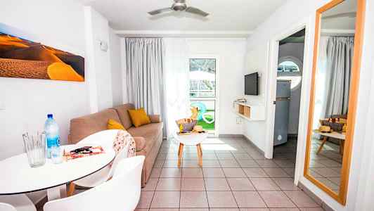 En stue med en sofa, et afsætningsbord, et spejl og et spisebord med stole. (AI-genereret tekst)