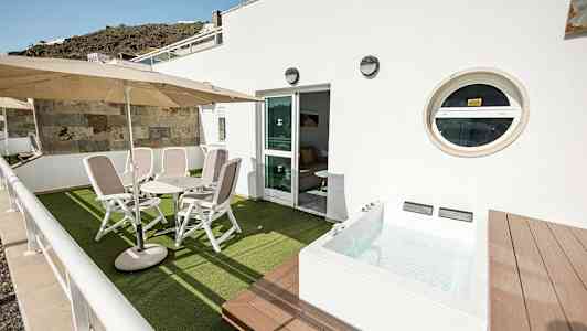 Terrasse med stole, bord og en lille pool. (AI-genereret tekst)