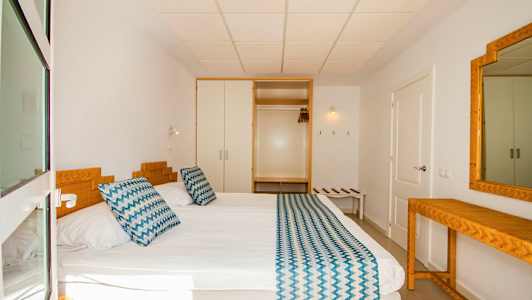 Et hotelværelse med en seng, sengetøj og et spejl. (AI-genereret tekst)