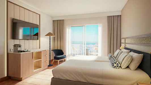 Et hotelværelse med to senge, et fladskærms-tv på væggen, møbler og en balkon med udsigt over havet. (AI-genereret tekst)