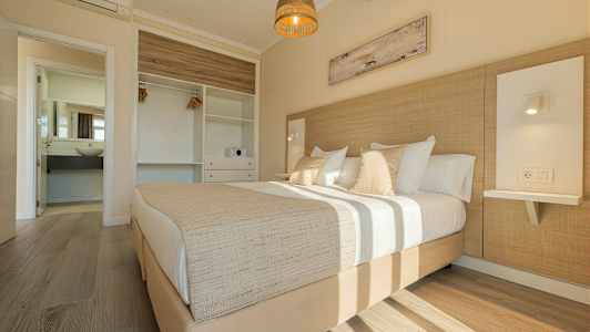 Et lyst soveværelse med en dobbeltseng, garderobe og åbent badeværelse. (AI-genereret tekst)