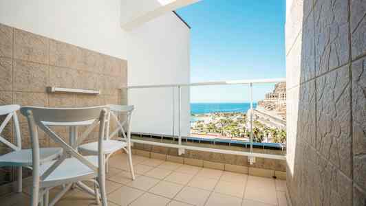 Hotelaltan med to stole og bord, med udsigt over havet. (AI-genereret tekst)