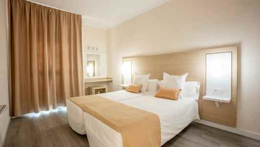 Hotelværelse med to enkeltsenge, beige og hvidt farvetema. (AI-genereret tekst)