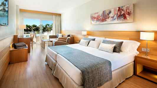 Et hotelværelse med en dobbeltseng, siddeområde og balkon med udsigt. (AI-genereret tekst)