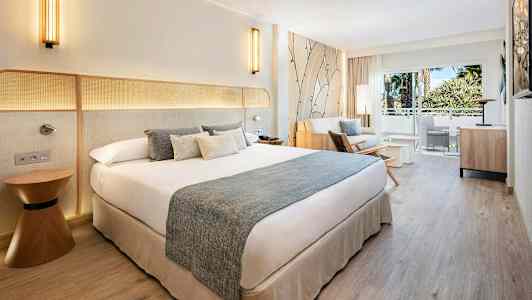 Hotelværelse med dobbeltseng, sofagruppe og altan med udsigt. (AI-genereret tekst)